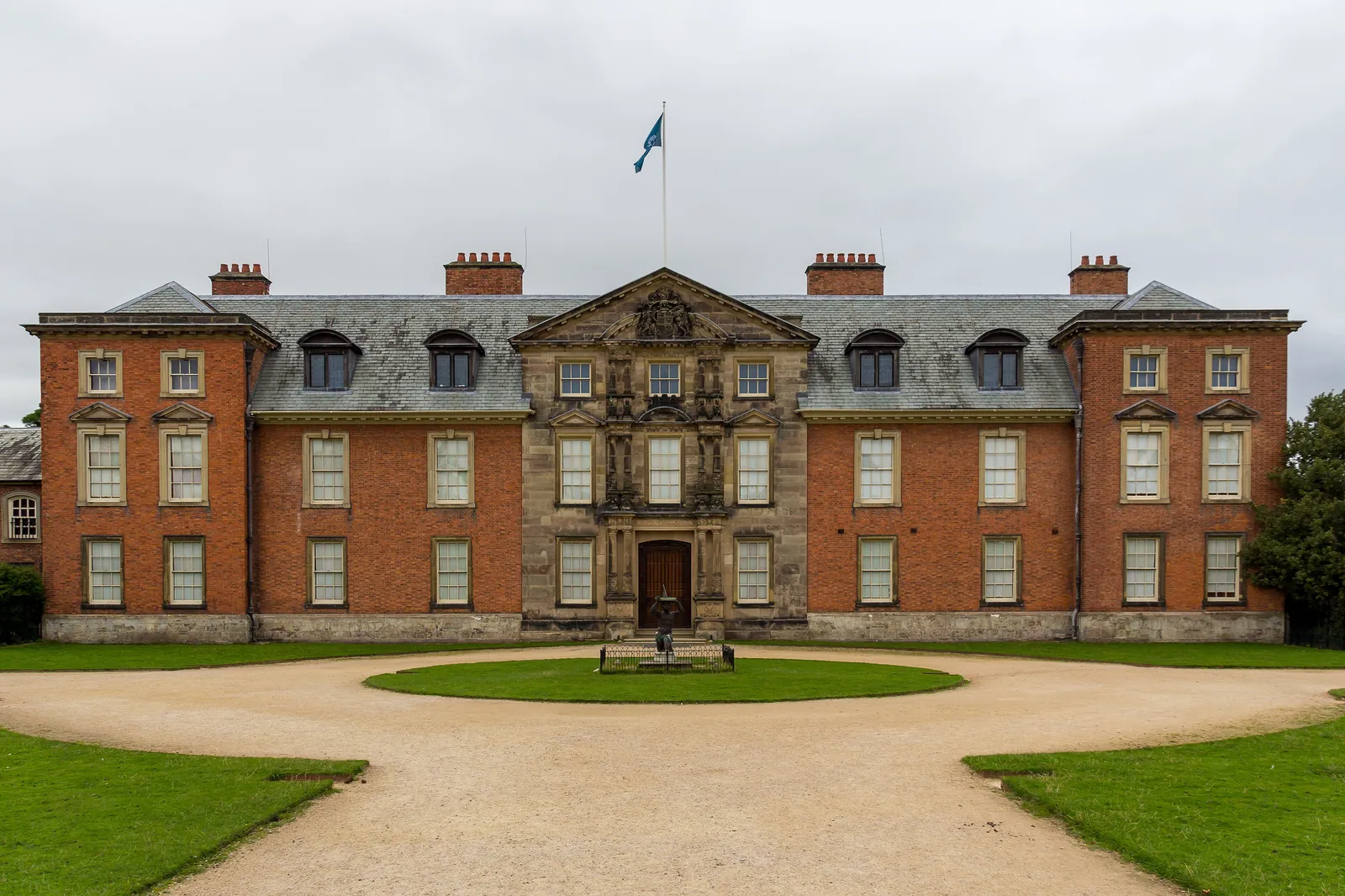 The red-brick front of Dunham Massey Hall behind its gravel forecourt and lawns