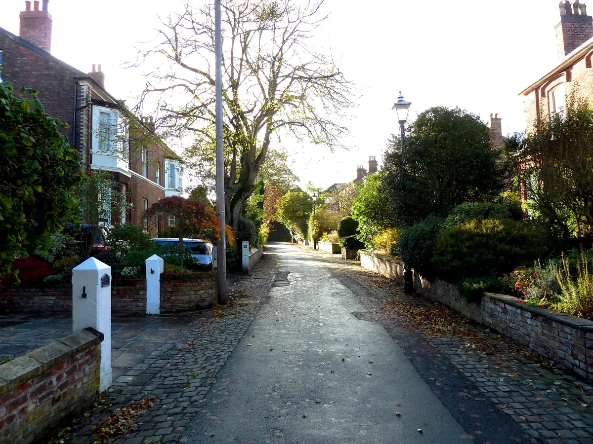 A leafy lane of Victorian houses behind low garden walls on Lyme Grove, Altrincham