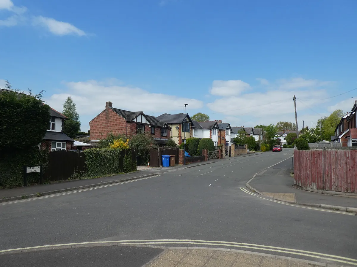 Brick and mock Tudor detached houses behind hedges along Western Road in Mickleover
